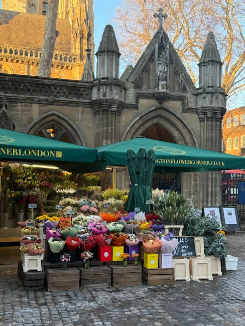 A vibrant outdoor flower stall in front of a historic stone church building with gothic architectural details, including pointed arches and decorative spires. The stall features an array of fresh flow